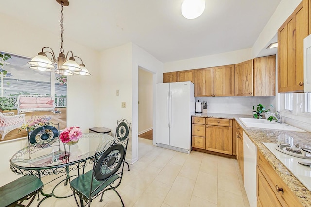 kitchen featuring baseboards, an inviting chandelier, hanging light fixtures, white appliances, and a sink