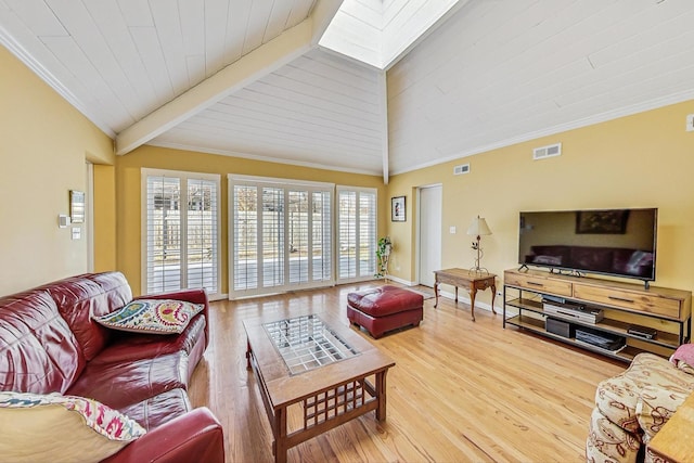 living area featuring lofted ceiling with skylight, visible vents, and wood finished floors