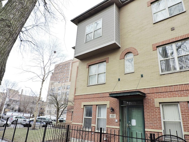 view of front of house featuring fence and brick siding