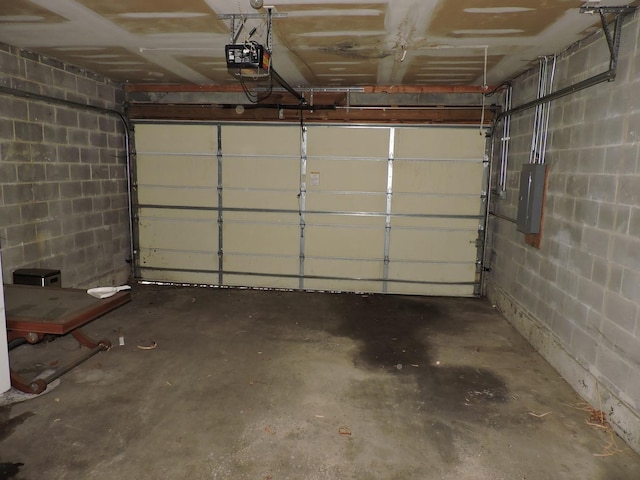 garage with electric panel, concrete block wall, and a garage door opener