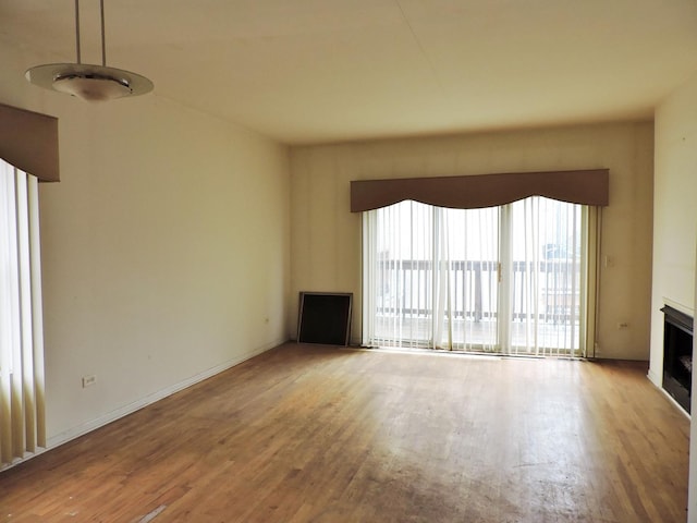 unfurnished living room featuring a fireplace, wood finished floors, and baseboards