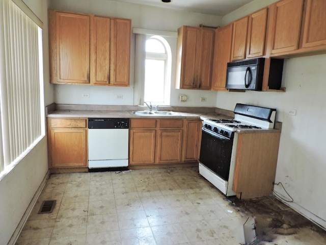 kitchen with white appliances, brown cabinetry, light floors, visible vents, and a sink