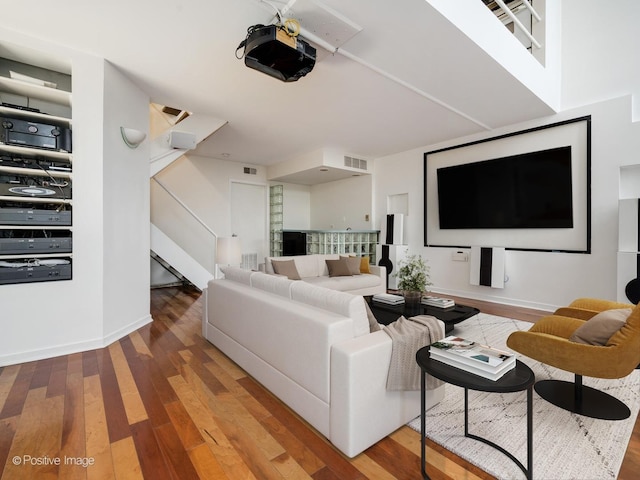 living room featuring stairs, wood finished floors, visible vents, and baseboards