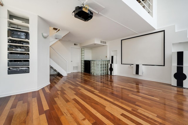 home theater room featuring visible vents, hardwood / wood-style floors, and a dry bar