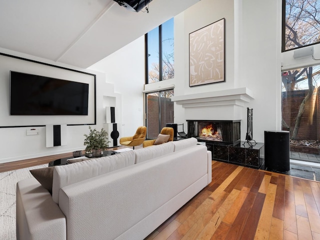 living area with hardwood / wood-style floors, a high ceiling, and a tile fireplace