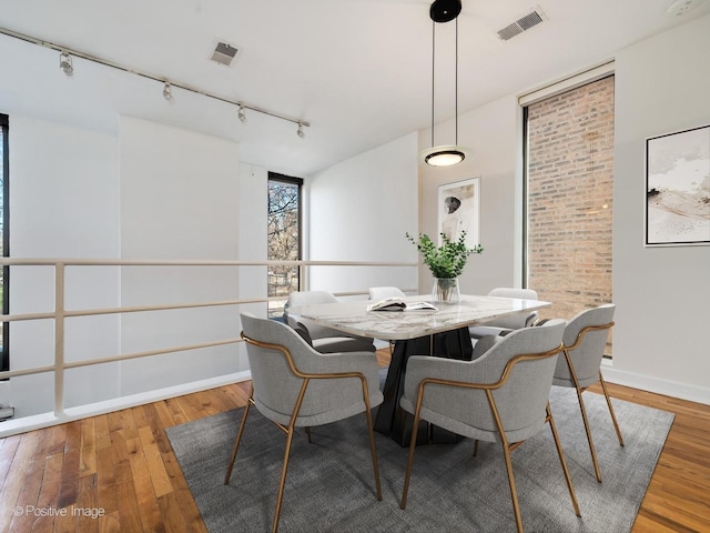 dining area with hardwood / wood-style flooring, baseboards, visible vents, and track lighting