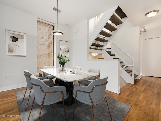 dining room with visible vents, stairs, baseboards, and hardwood / wood-style flooring