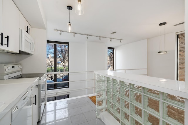 kitchen featuring visible vents, white appliances, white cabinets, light tile patterned floors, and hanging light fixtures