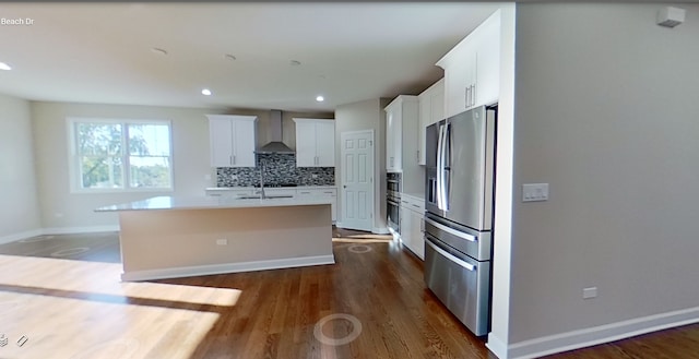 kitchen with backsplash, wall chimney range hood, dark wood finished floors, an island with sink, and stainless steel refrigerator with ice dispenser