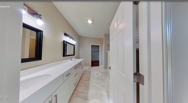 full bathroom featuring a sink, marble finish floor, a spacious closet, and double vanity