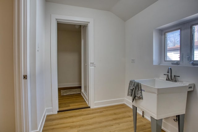 laundry area with a sink, baseboards, and light wood-style floors