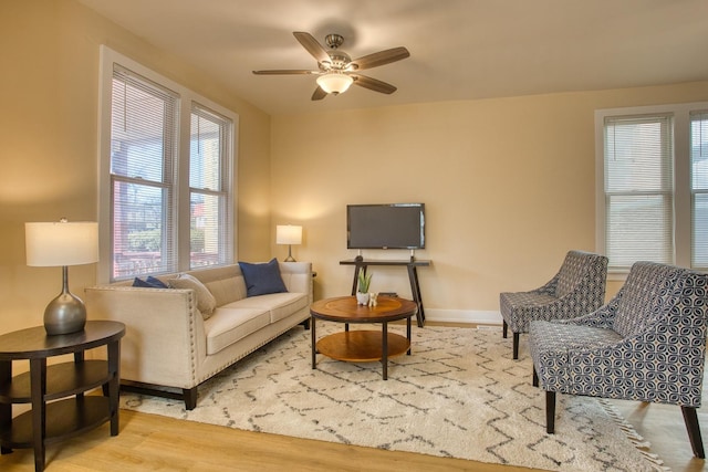 living area featuring wood finished floors, baseboards, and ceiling fan