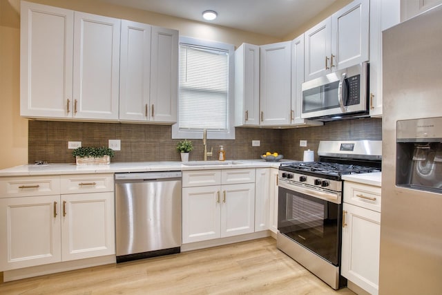 kitchen with a sink, light countertops, light wood-type flooring, and stainless steel appliances