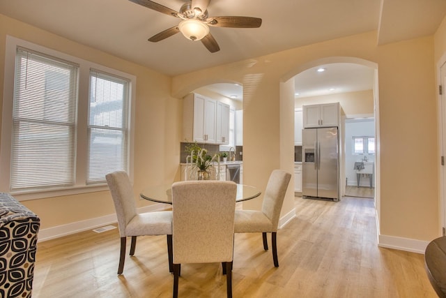 dining room with baseboards, arched walkways, visible vents, and light wood-style flooring