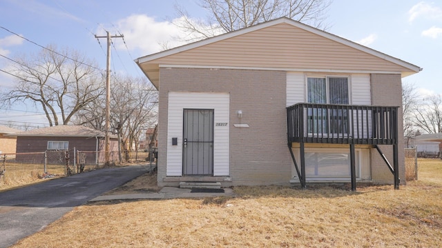 view of front of home with fence, brick siding, driveway, and entry steps