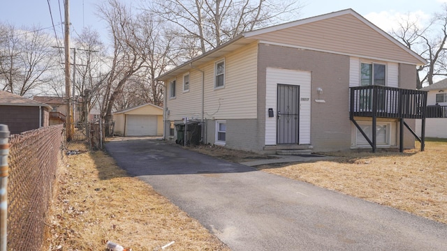 view of front of house featuring fence, aphalt driveway, an outdoor structure, a detached garage, and brick siding