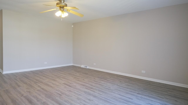 empty room with a ceiling fan, baseboards, and wood finished floors