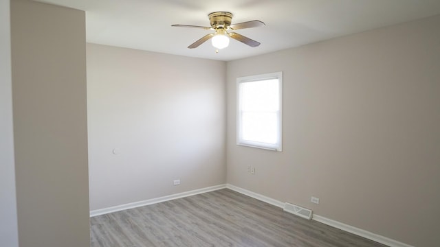 spare room with visible vents, baseboards, wood finished floors, and a ceiling fan