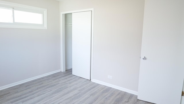 unfurnished bedroom with a closet, baseboards, and light wood-style floors