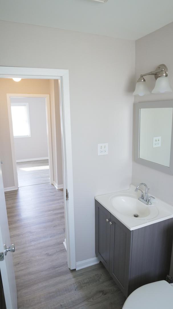 bathroom featuring toilet, vanity, baseboards, and wood finished floors