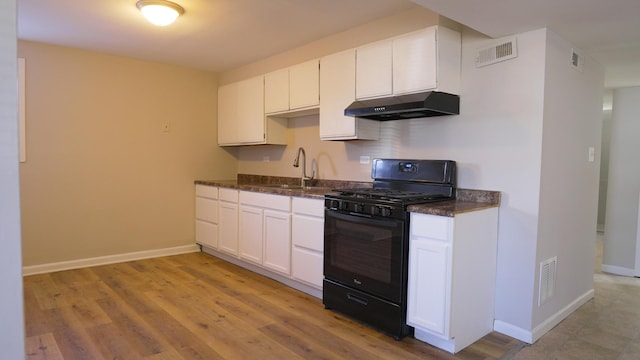 kitchen with under cabinet range hood, black range with gas stovetop, visible vents, and a sink