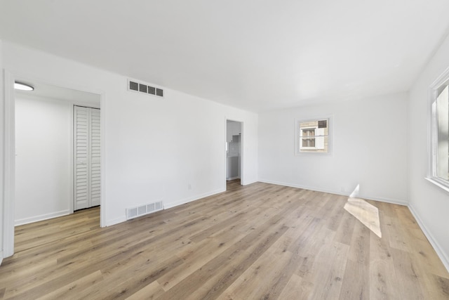 spare room with light wood-type flooring, a healthy amount of sunlight, and visible vents