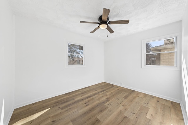 spare room with plenty of natural light, wood finished floors, and baseboards