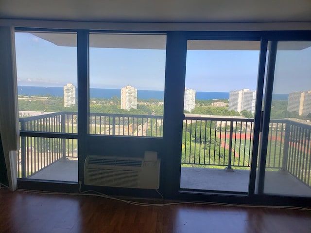 doorway with a view of city, a wall unit AC, and wood finished floors