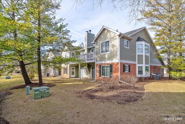 view of front of property featuring cooling unit, a front yard, brick siding, and a chimney