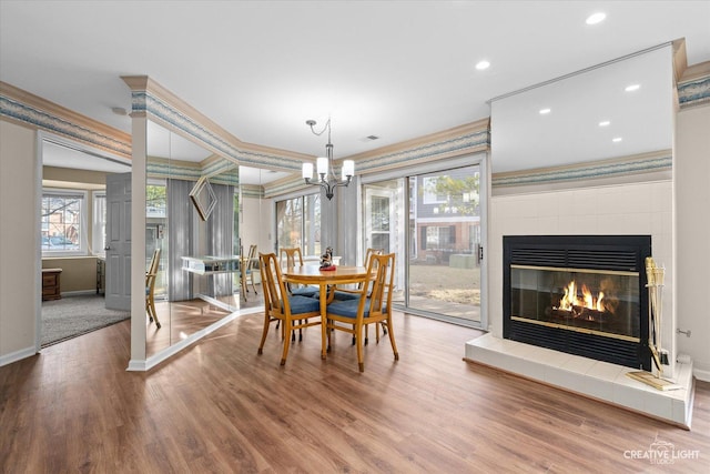 dining space with wood finished floors, recessed lighting, a fireplace, crown molding, and baseboards