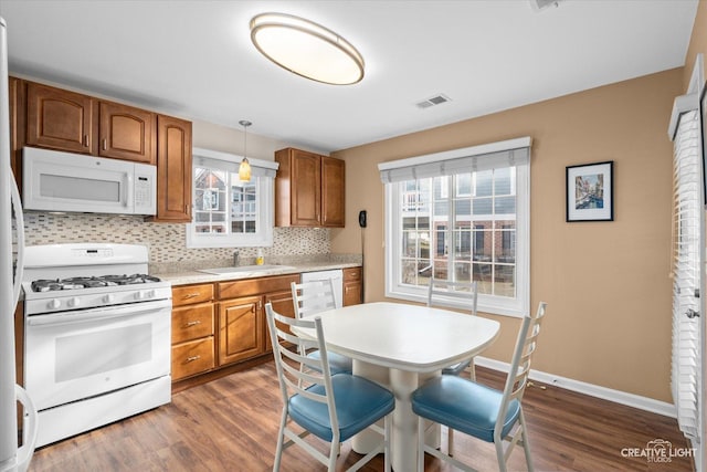 kitchen featuring visible vents, brown cabinets, white appliances, and a sink