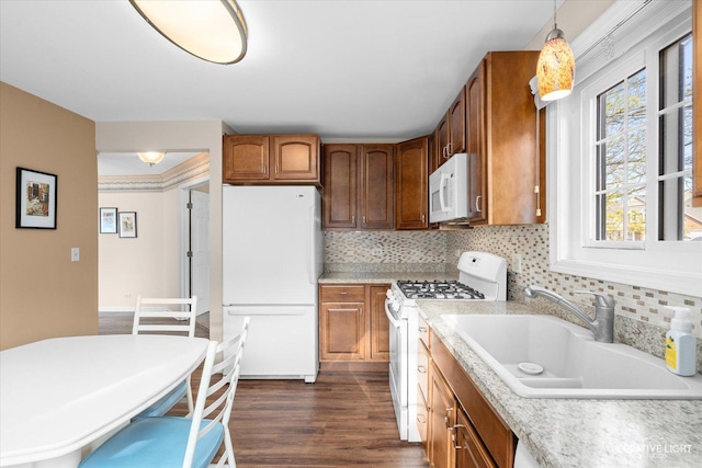 kitchen with white appliances, dark wood finished floors, a sink, light countertops, and brown cabinets