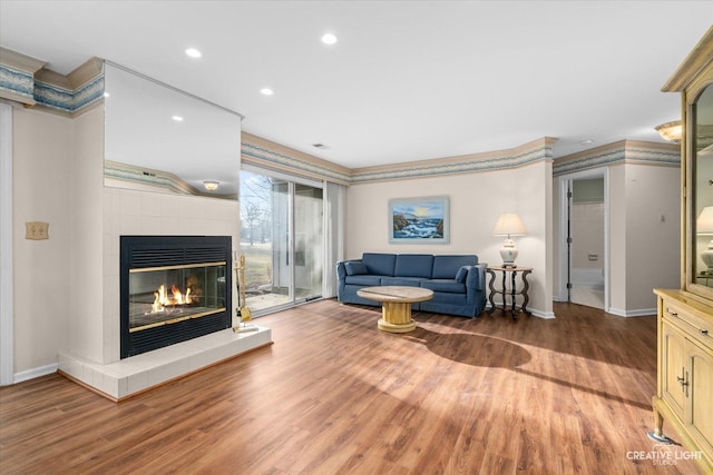 living area featuring recessed lighting, baseboards, wood finished floors, and a tiled fireplace