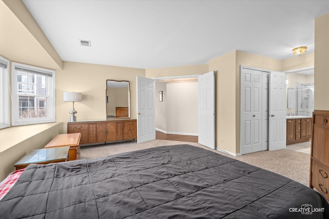 bedroom featuring visible vents, connected bathroom, baseboards, light carpet, and a closet