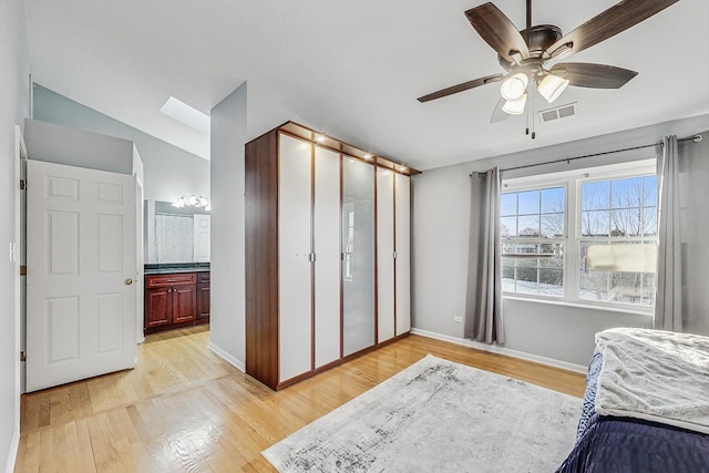 bedroom featuring a ceiling fan, light wood-style floors, visible vents, and baseboards