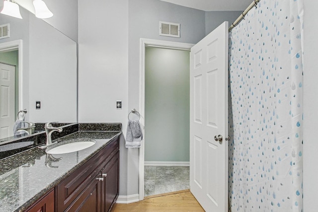 bathroom with visible vents, baseboards, wood finished floors, and vanity