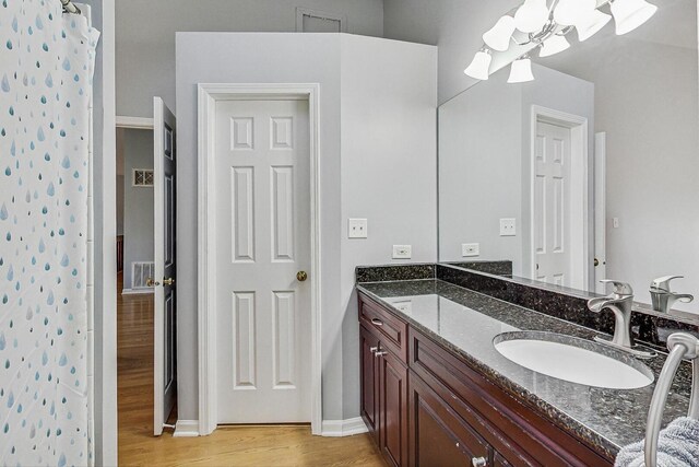 bathroom featuring vanity, curtained shower, a notable chandelier, and wood finished floors