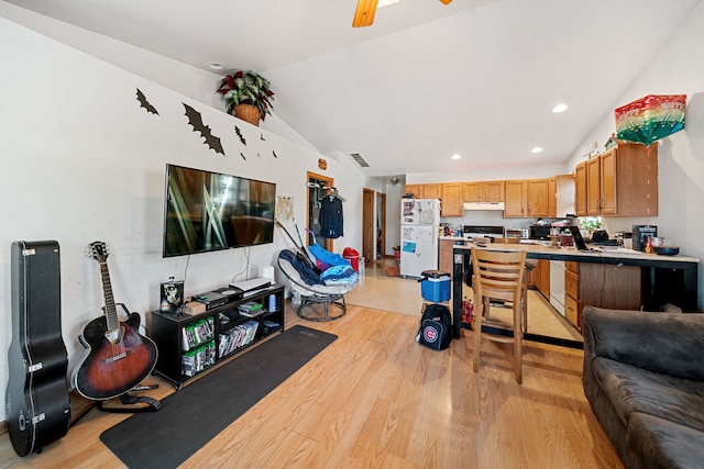 interior space featuring under cabinet range hood, open floor plan, lofted ceiling, light wood-style flooring, and freestanding refrigerator