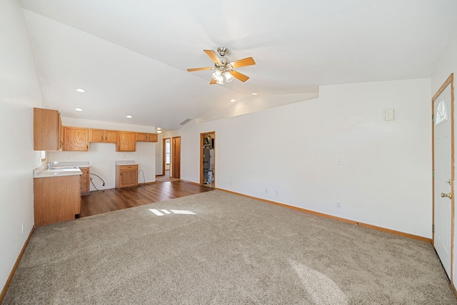 unfurnished living room with dark colored carpet, baseboards, lofted ceiling, and ceiling fan