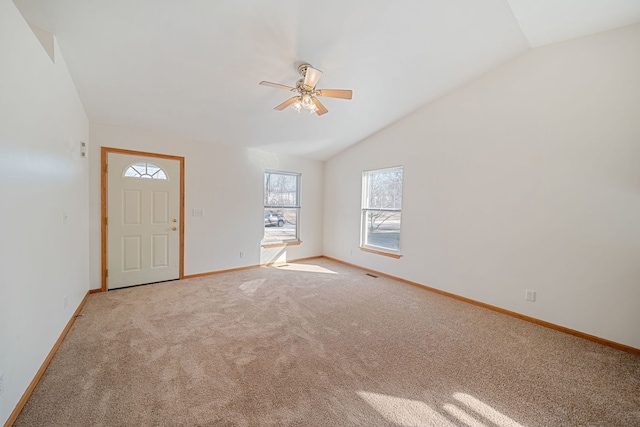 interior space with light colored carpet, ceiling fan, baseboards, and vaulted ceiling