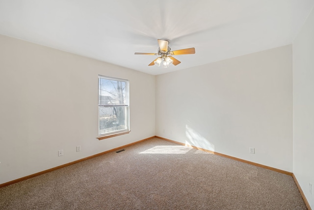 carpeted spare room featuring visible vents, ceiling fan, and baseboards