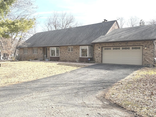 view of front of house featuring brick siding, driveway, a garage, and roof with shingles