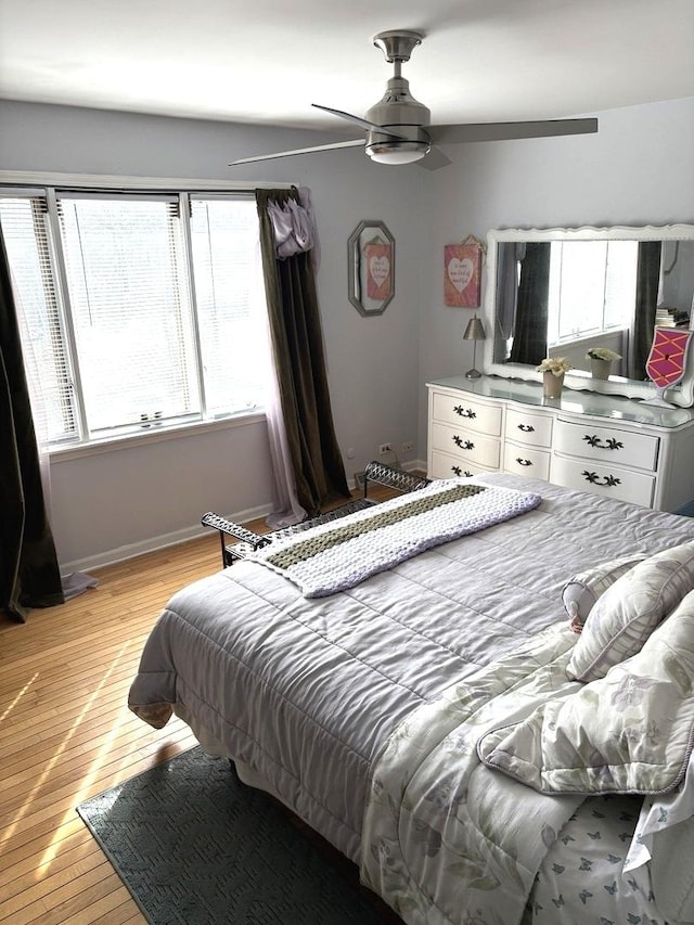 bedroom with a ceiling fan, light wood-style floors, and baseboards