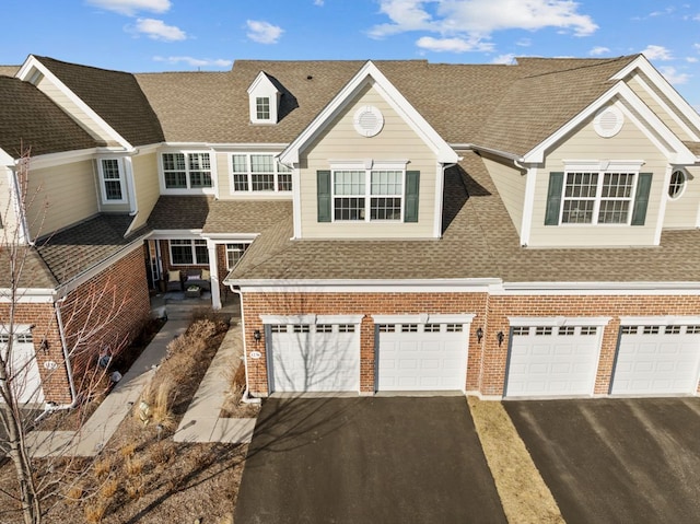 view of front of property with aphalt driveway, brick siding, a garage, and a shingled roof