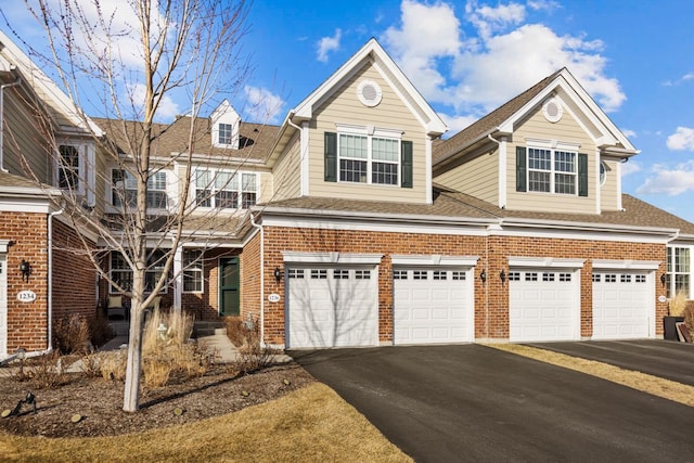 view of front facade featuring aphalt driveway, an attached garage, brick siding, and a shingled roof