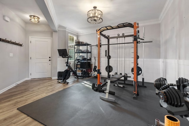 workout room featuring crown molding, baseboards, and wood finished floors