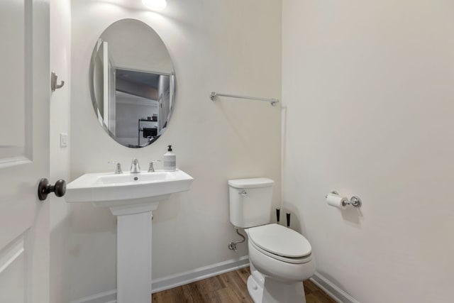 bathroom featuring a sink, baseboards, toilet, and wood finished floors