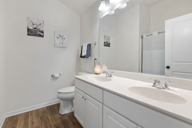 bathroom with double vanity, toilet, wood finished floors, and a sink