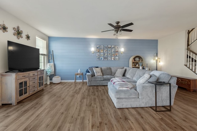 living room with ceiling fan, baseboards, wood finished floors, and stairs