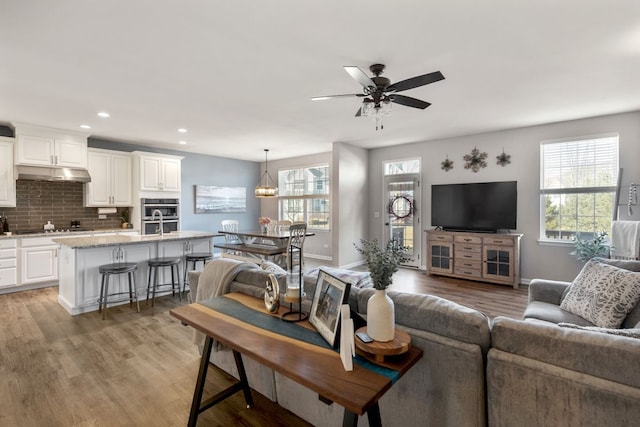 living area featuring light wood-style flooring, recessed lighting, a ceiling fan, and baseboards